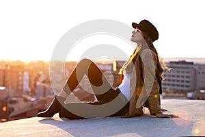 Pretty young woman enjoying time and sunset while sitting on the rooftop