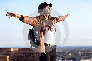 Pretty young woman enjoying time and sunset while standing on the rooftop