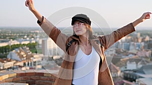 Pretty young woman enjoying time and sunset while standing on the rooftop.