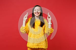 Pretty young woman in fur sweater wait for special moment, keeping fingers crossed, eyes closed, making wish isolated on