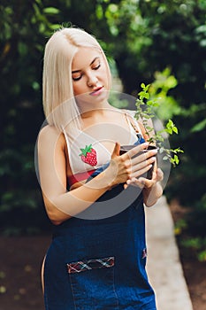 Pretty young woman gardening in an apron, without clothes.