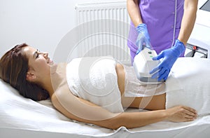 Pretty young woman getting cryolipolyse treatment in cabinet