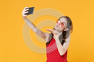 Pretty young woman girl in red summer dress, eyeglasses posing isolated on yellow background. People lifestyle concept