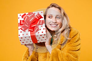 Pretty young woman girl in yellow fur coat isolated on orange background. St. Valentine`s Day, International Women`s Day