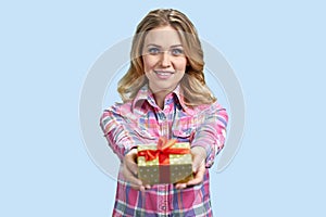 Pretty young woman giving beautiful gift box to camera.