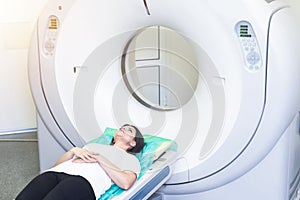 Pretty, young woman goiing through a Computerized Axial Tomography CAT Scan medical test examination in a modern