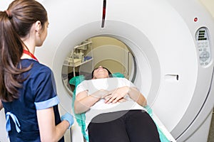 Pretty, young woman goiing through a Computerized Axial Tomography CAT Scan medical test examination in a modern