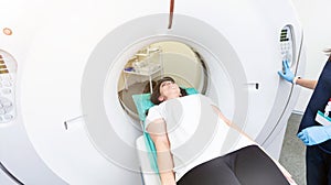 Pretty, young woman goiing through a Computerized Axial Tomography CAT Scan medical test examination in a modern