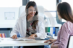 Pretty young woman gynecologist reviewing the documents of her pregnant patient in the clinic photo