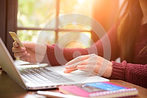 Pretty Young woman hands holding a credit card and using laptop