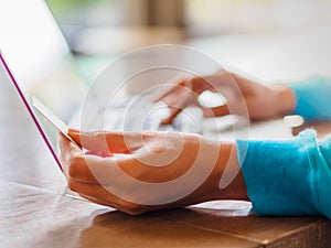 Pretty Young woman hands holding a credit card and using laptop computer for online shopping.