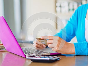 Pretty Young woman hands holding a credit card and using tablet, smartphone and laptop computer for online shopping.