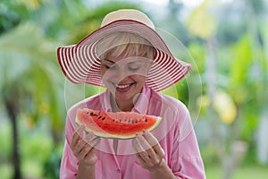 Pretty Young Woman In Hat Holding A Slice Of Watermelon And Smiling Happy Over Tropical Forest Background