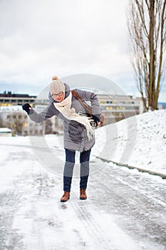 Pretty, young woman having troubles walking on an icy