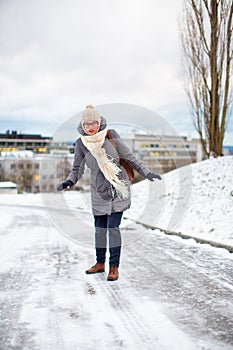 Pretty, young woman having troubles walking on an icy photo