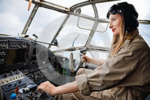 Pretty young woman in a helmet and pilot`s suit sits in the cabin