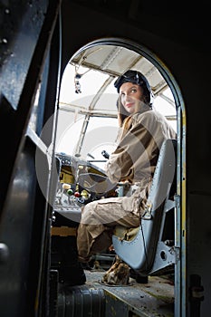 Pretty young woman in a helmet and pilot`s suit sits in the cockpit