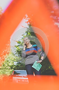 Pretty, young woman with her car broken down by the roadside