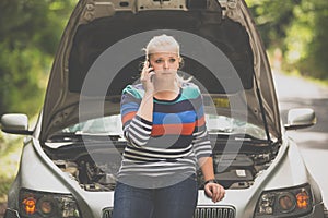 Pretty, young woman with her car broken down by the roadside