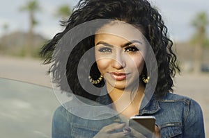 Pretty young woman beside her car making phone call