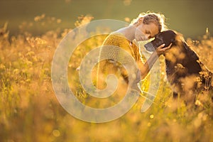 Pretty, young woman with her large black dog on a lovely sunlit meadow