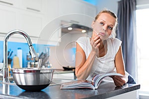 Pretty, young woman in her modern, clean and bright kitchen