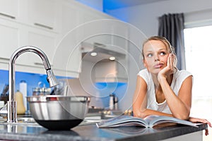 Pretty, young woman in her modern, clean and bright kitchen