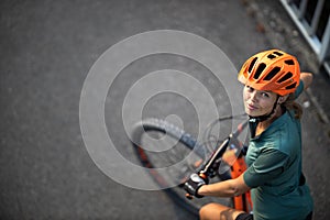 Pretty, young woman with her mountain bike going for a ride past the city limits,