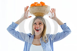 Pretty young woman holding a bowl over her head with oranges over white background