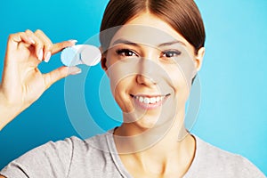 Pretty young woman holding a container with contact lenses for eyesight
