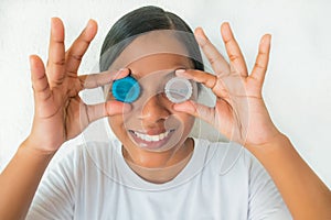 Pretty young woman holding a container with contact lenses for eyesight