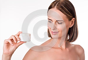 Pretty young woman holding cream