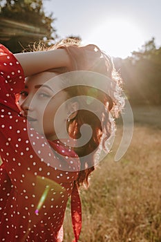 Pretty young woman holding her hair by hands and posing on a camera on the middle of wheat field