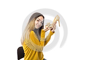 Pretty young woman holding a high heel shoe over white background