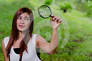 Pretty young woman holding a magnifying glass