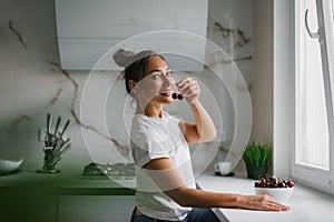 Pretty young woman holds a cherry berry in her hand and wants to eat it