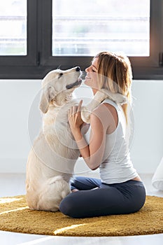 Pretty young woman hugging her dog while sitting on the floor at home