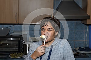 Pretty young woman hungrily eating ravioli from a fork