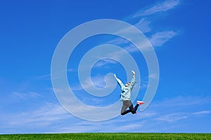 Pretty young woman jumping on green grass