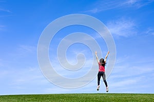 Pretty young woman jumping on green grass