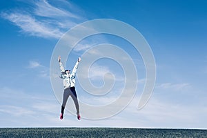 Pretty young woman jumping on green grass