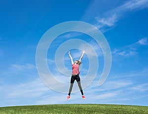 Pretty young woman jumping on green grass