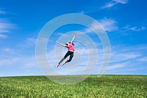 Pretty young woman jumping on green grass
