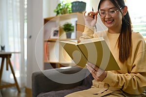 Pretty young woman listening to music with headphone and reading book at home