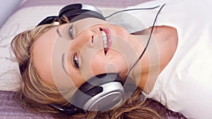 Pretty young woman listening to music looking at camera