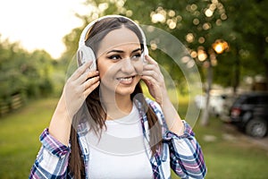 Pretty young woman listening to music outdoors