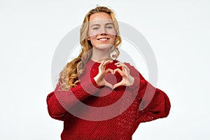 Pretty young woman with long blonde hair making a heart with her hands