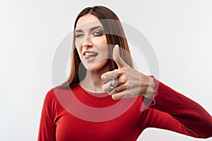 Pretty Young woman with long chestnut hair looking at the camera and pointing her finger at you. Human emotions concept