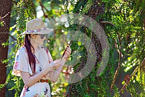 Young Woman Examining A Spiky Leaf In Garden