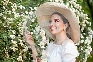 Pretty young woman looking at flowers outdoors